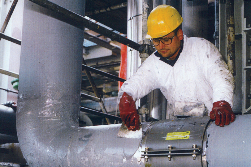 Insulation adhesive being applied to industrial pipe