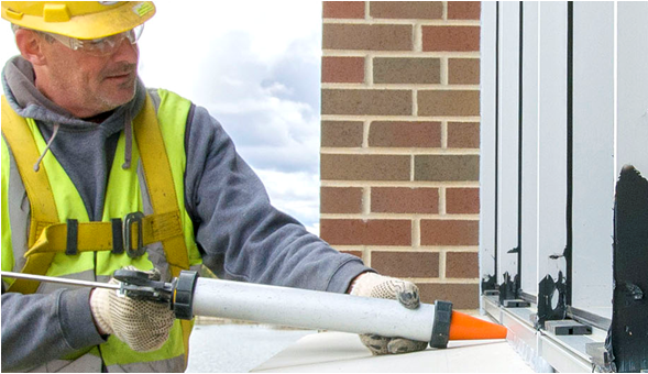 Worker applying sealant to window